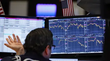 A trader sits in front of two computer screens A trader sits in front of two computer screens