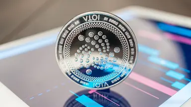 Iota coin standing on a digital device