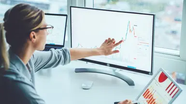 A businesswoman points to a graph on a screen 