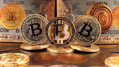 Physical bitcoins pictured in front of a backdrop of notes