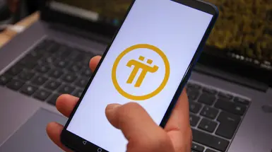 Hand holding a smartphone bearing the Pi Network logo Hand holding a smartphone bearing the Pi Network logo