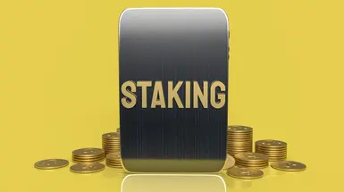 Image of block with word 'staking' on yellow background, surrounded by crypto tokens Image of block with word 'staking' on yellow background, surrounded by crypto tokens